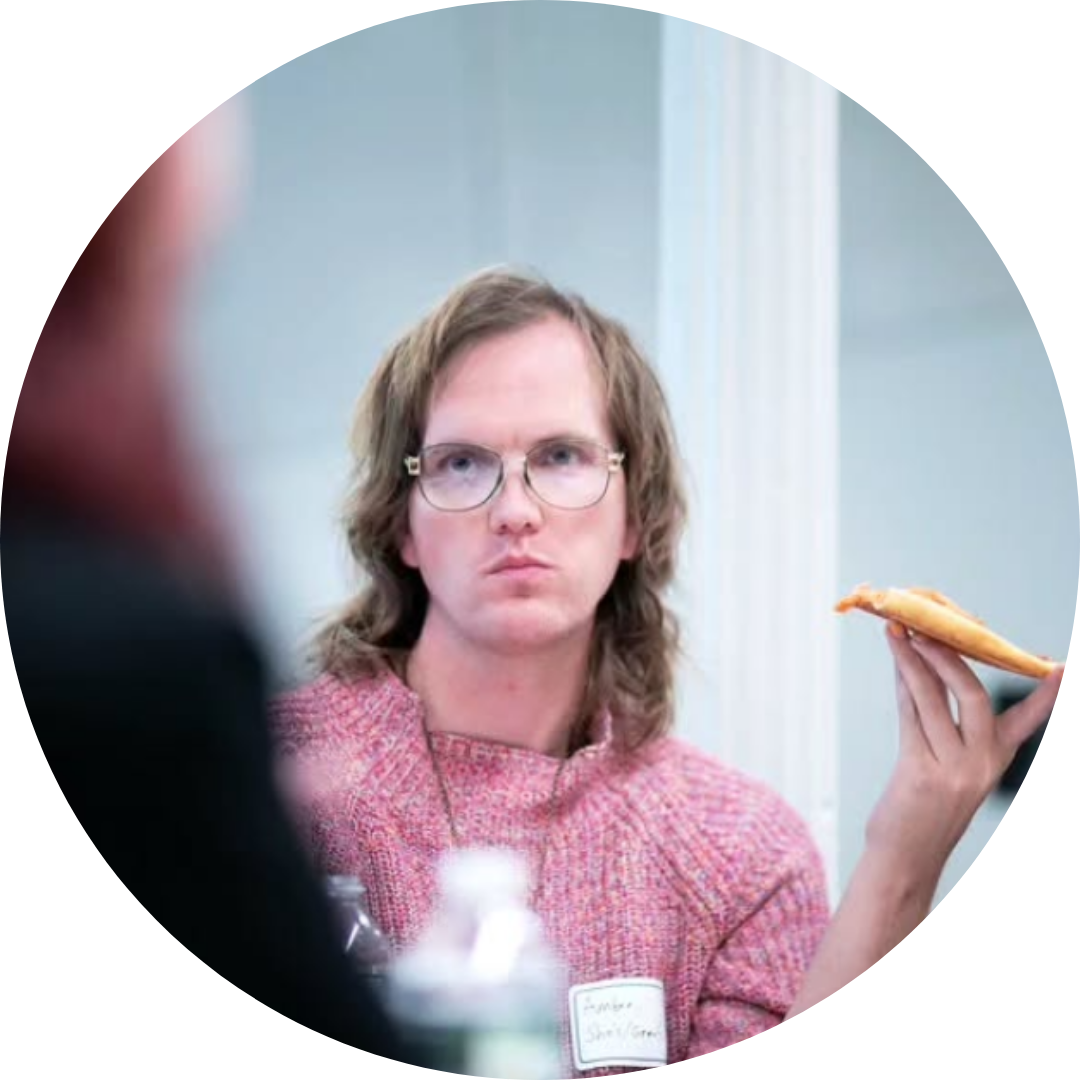 Amber Flannery Field with glasses and a pink shirt eating a slice of pizza