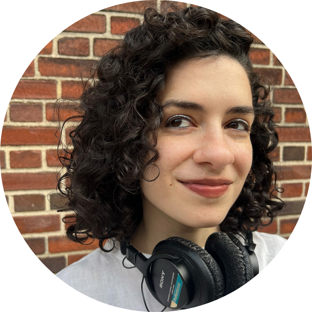 Rebecca Seidel, a person with curly hair wearing headphones in front of a brick wall